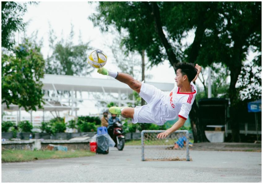 Young Asian male soccer player executing a high ju