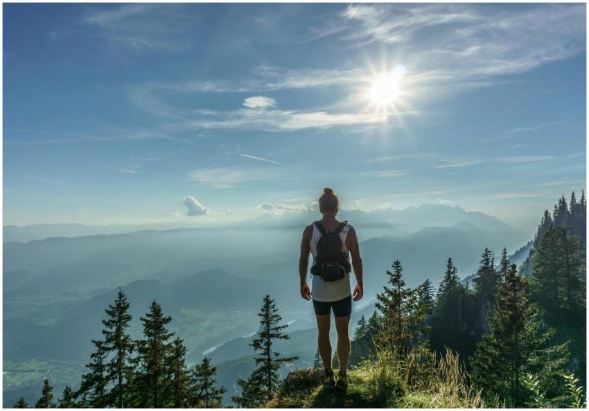 A lone hiker stands on a mountain top, overlooking