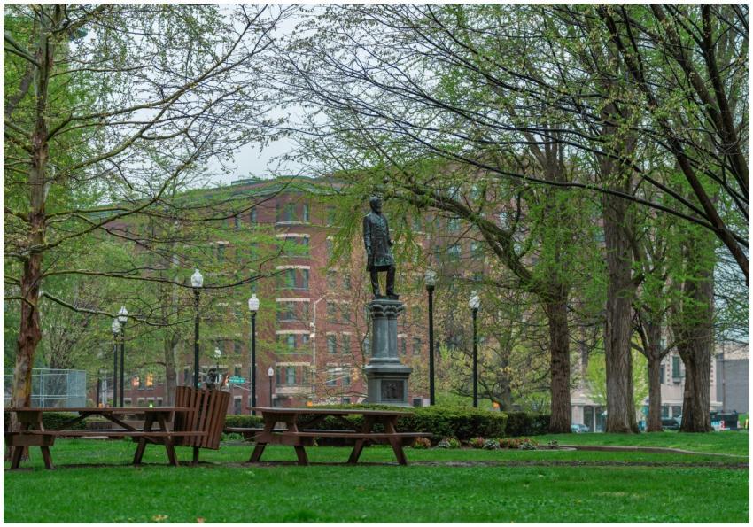 A statue in a city park with lush green lawns and