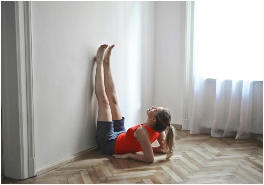 A woman in a red top performs a yoga stretch with