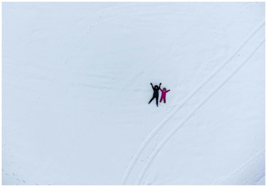 Aerial shot of two people lying in snow making sno