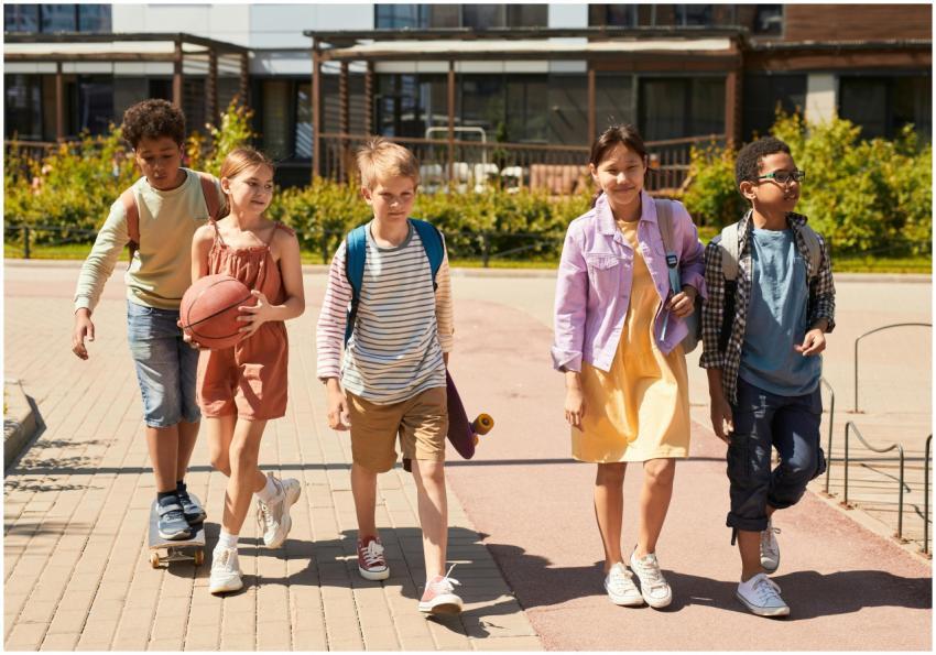 A diverse group of children walking outdoors, carr