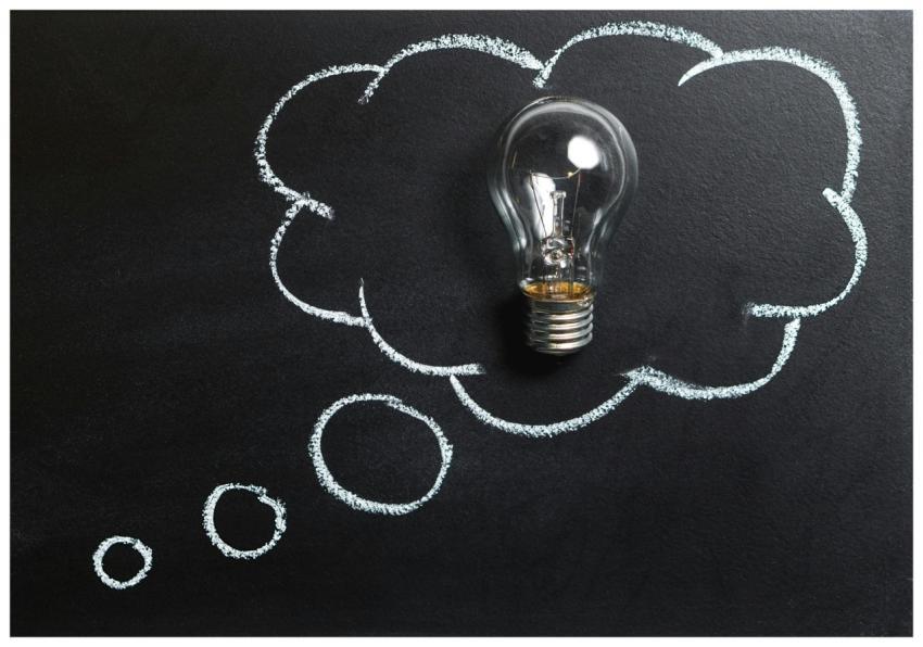 Light bulb laying on chalkboard with drawn thought