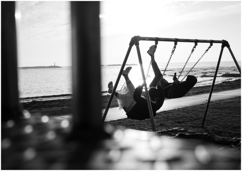 A couple enjoys swinging together by the seaside,