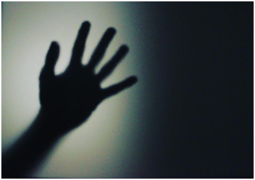 A shadowy silhouette of a hand in front of a softl