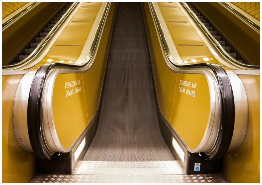 A sleek yellow escalator indoors, highlighting mod