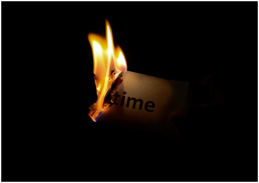 A close-up of a paper with the word 'time' burning