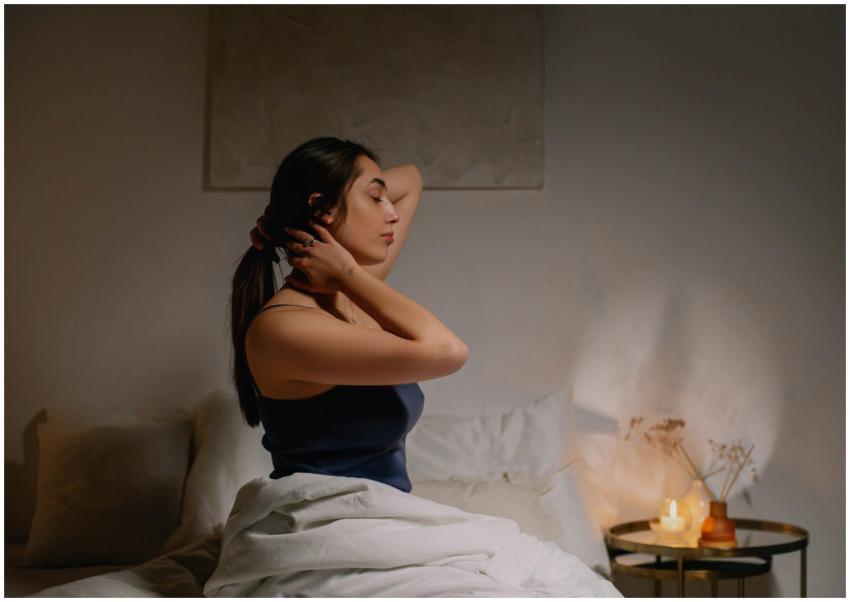 A calm woman sits on a bed in a cozy bedroom, enjo