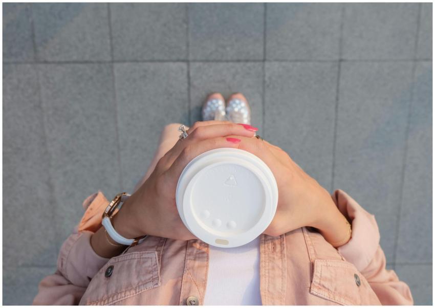 Top view of a woman holding a coffee cup outdoors,