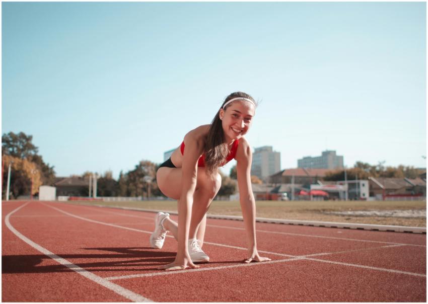 Smiling female athlete ready to start on an outdoo