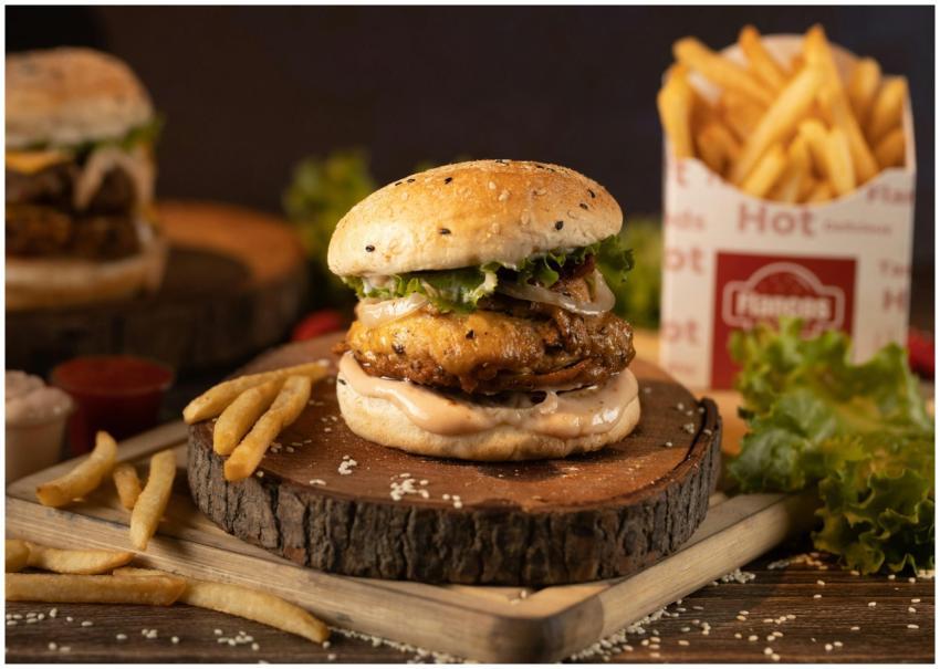 Juicy burger with lettuce and crispy fries on a wo