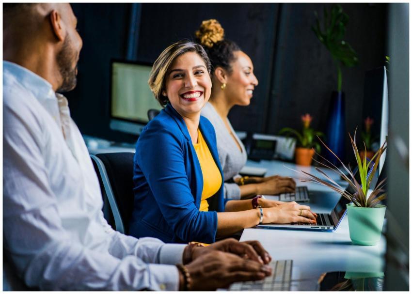 Three diverse professionals working and smiling at