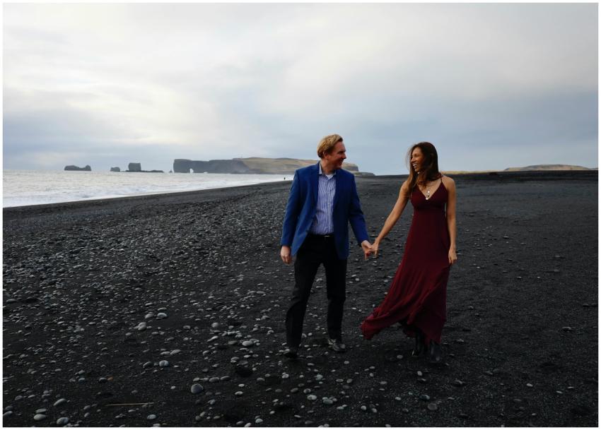 Couple walking hand in hand on the black sand beac