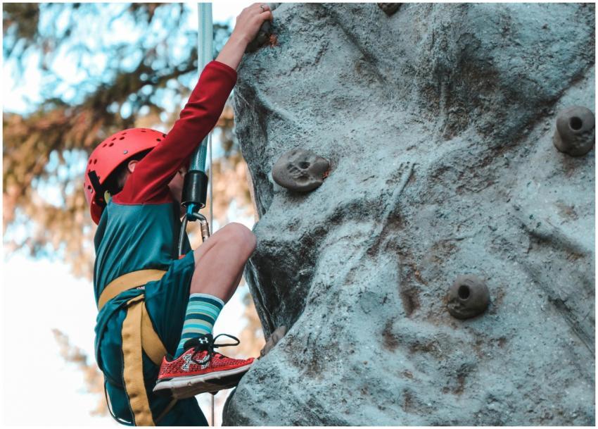 Young child rock climbing with safety gear, showca