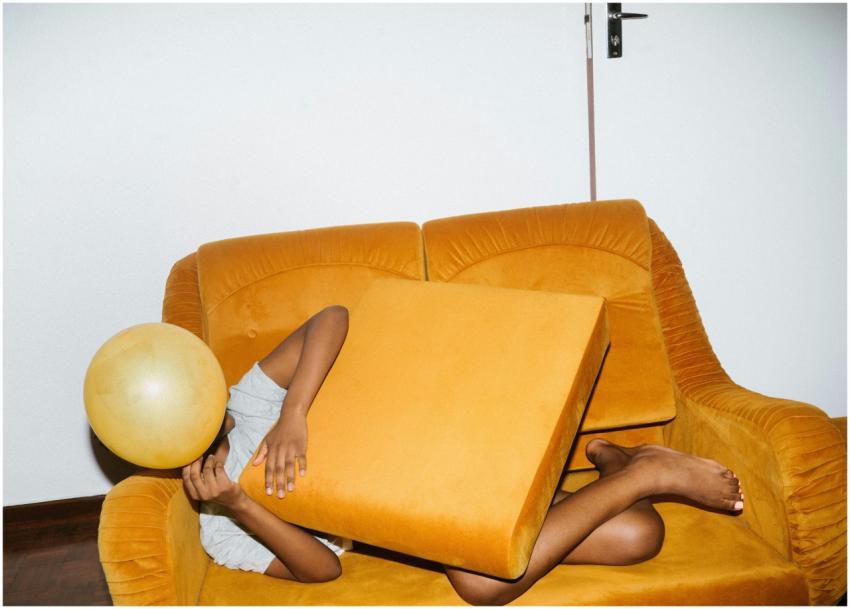 A person playfully relaxes on a vibrant yellow sof