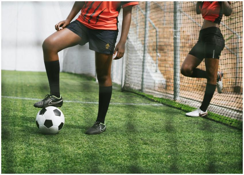 Two teenagers in soccer gear practicing on a footb