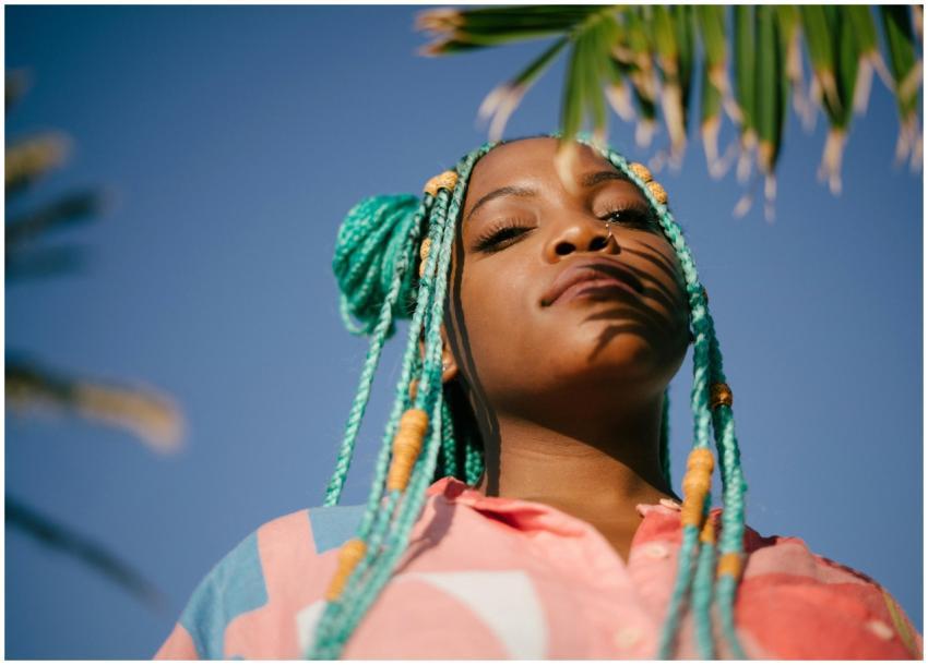 A confident woman with colorful braids enjoys a su