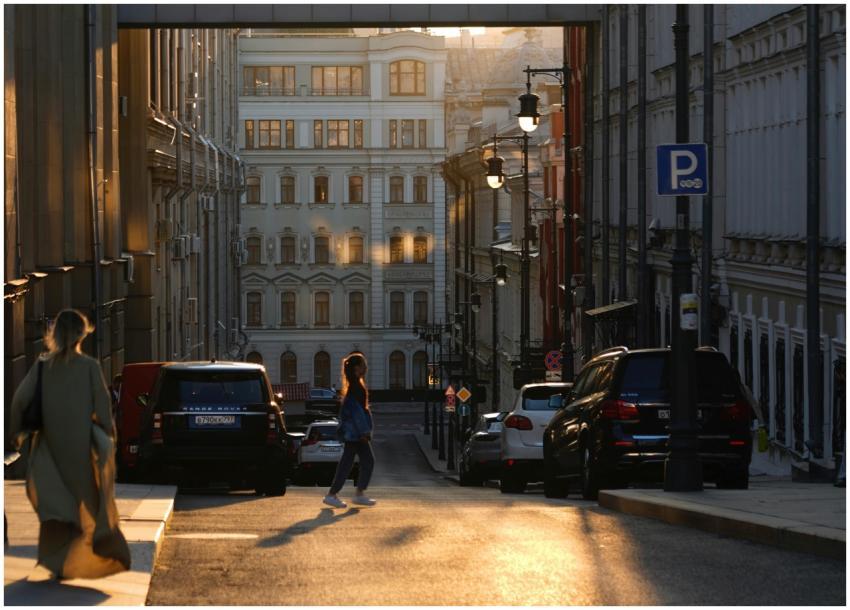 A serene city street at sunset with pedestrians an