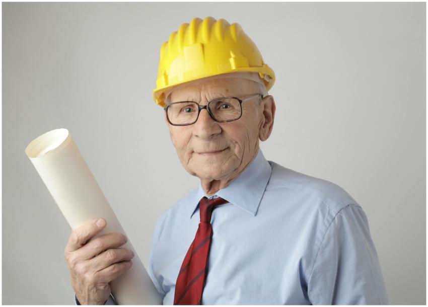 Senior engineer in safety gear holding blueprints,