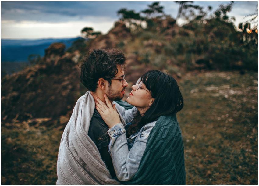 A young couple embraces warmly under a blanket in