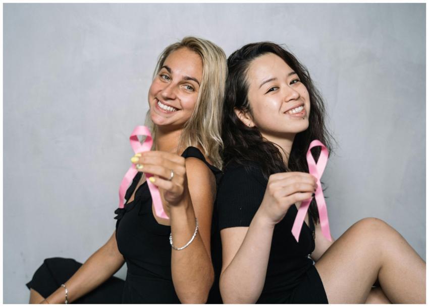 Two women holding pink ribbons to promote breast c