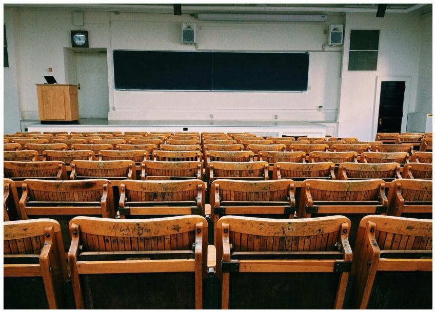 An empty lecture hall featuring wooden chairs and