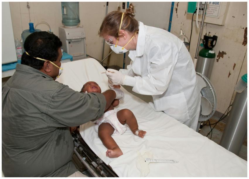 Doctor in protective gear treating a baby on a hos