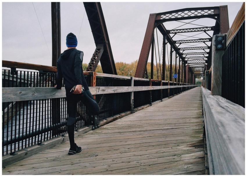 Man stretching on a wooden footbridge during a day