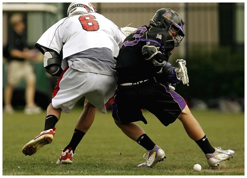 Competitive lacrosse match showing two players bat