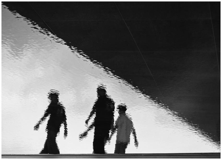 Silhouettes of three people reflected in rippling