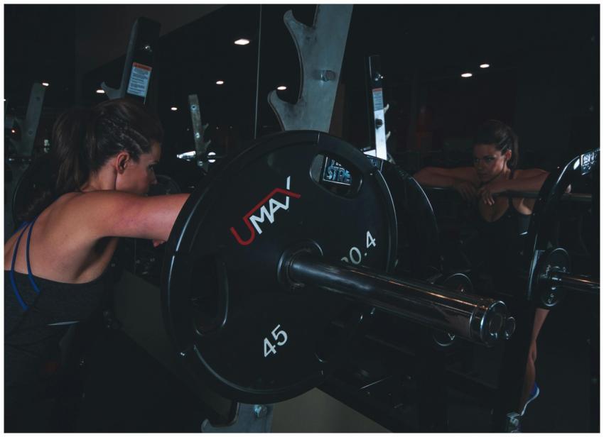 Woman in gym attire reflects in mirror while prepa