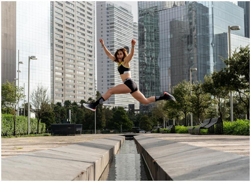 Woman leaping joyfully in an urban park, surrounde