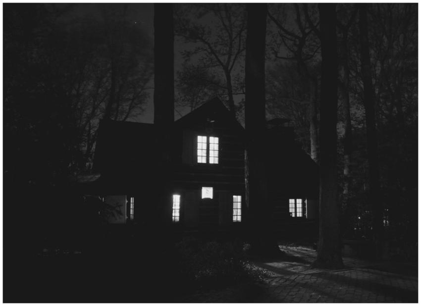 A haunting black and white image of a house surrou