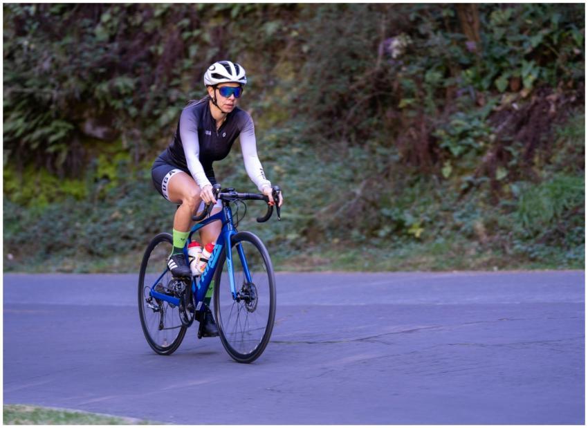Female cyclist riding a road bike on a quiet trail