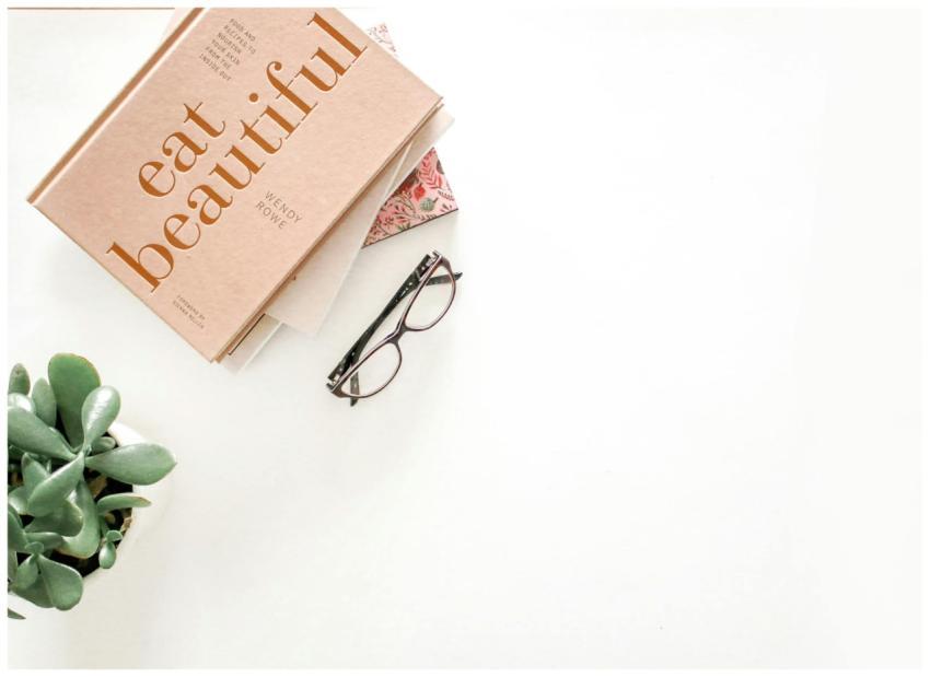 A minimalist flatlay featuring a book, eyeglasses,