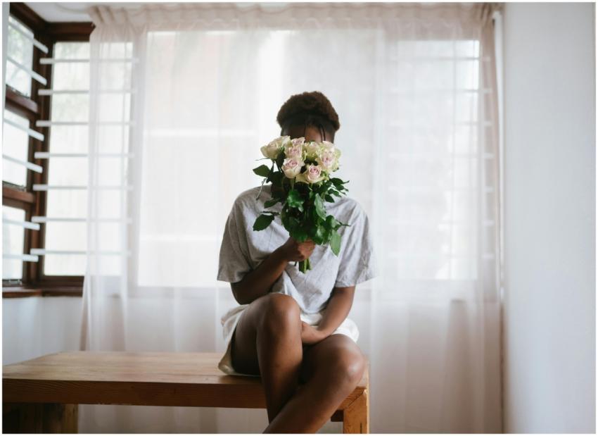 Woman sitting on a wooden table holding a bouquet