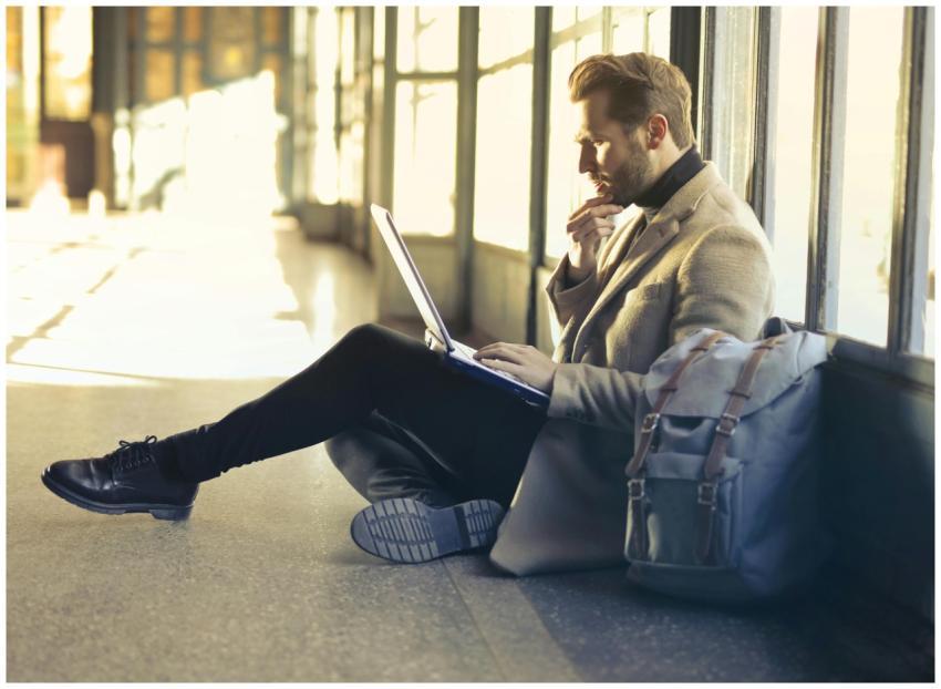 Young man sitting indoors at an airport using lapt