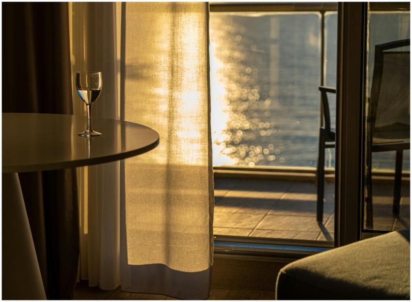 Sunlit room with a wine glass on table, overlookin