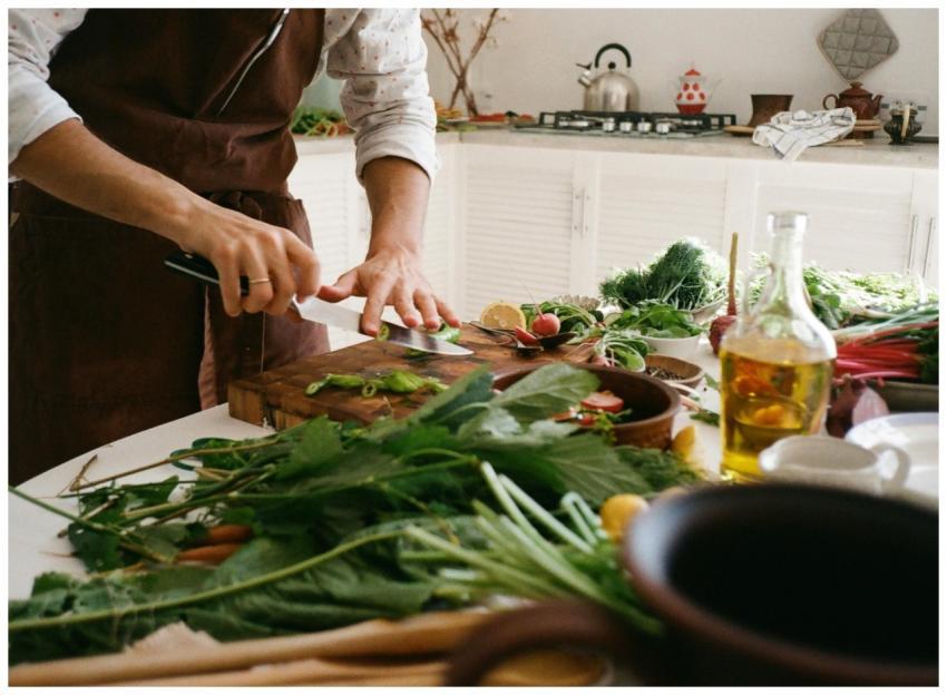 Adult preparing a fresh vegetable salad in a cozy