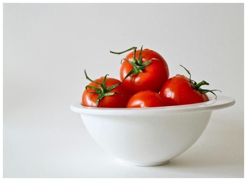 Vibrant red tomatoes in a white bowl, emphasizing