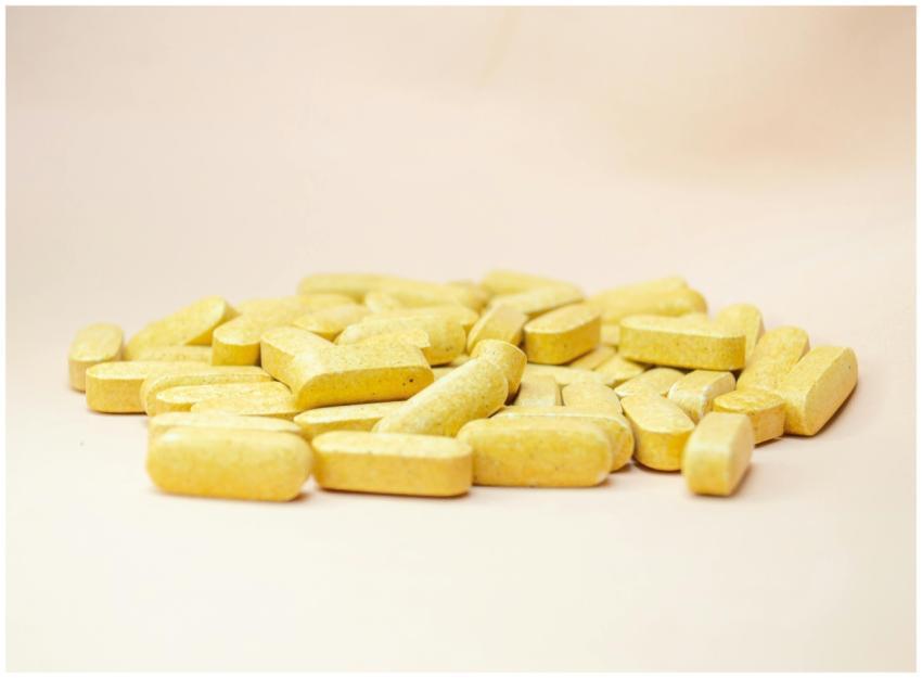 Close-up of scattered yellow vitamin tablets on a