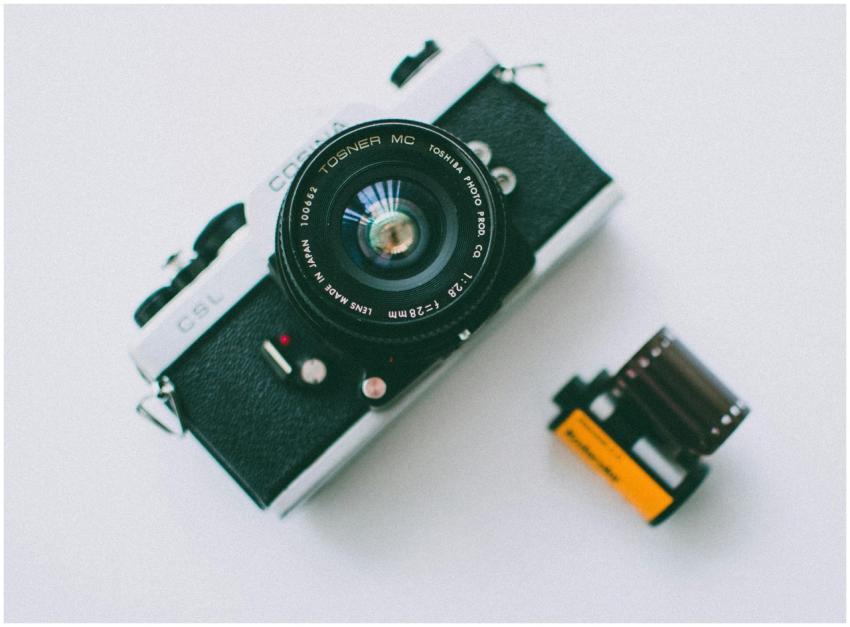 Close-up of a classic film camera and roll on a wh