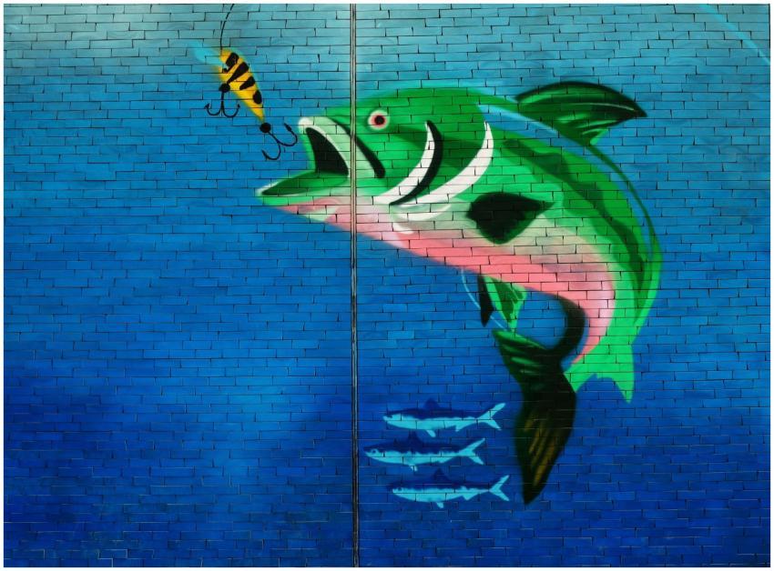 Vibrant mural of a fish and bait on a brick wall,