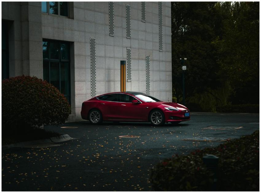 A sleek red electric car parked beside a modern bu