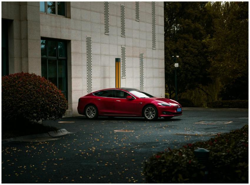 A stylish red electric car parked beside a modern
