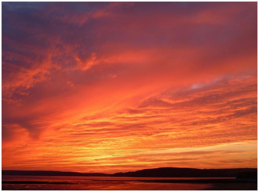 Stunning red sunset with vivid clouds reflecting o