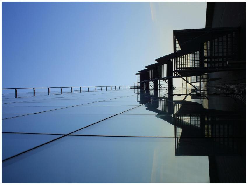 A striking glass skyscraper reflecting blue skies,