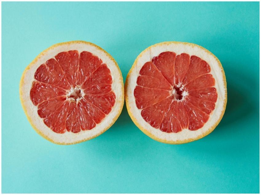 Two fresh grapefruit halves on a vibrant turquoise