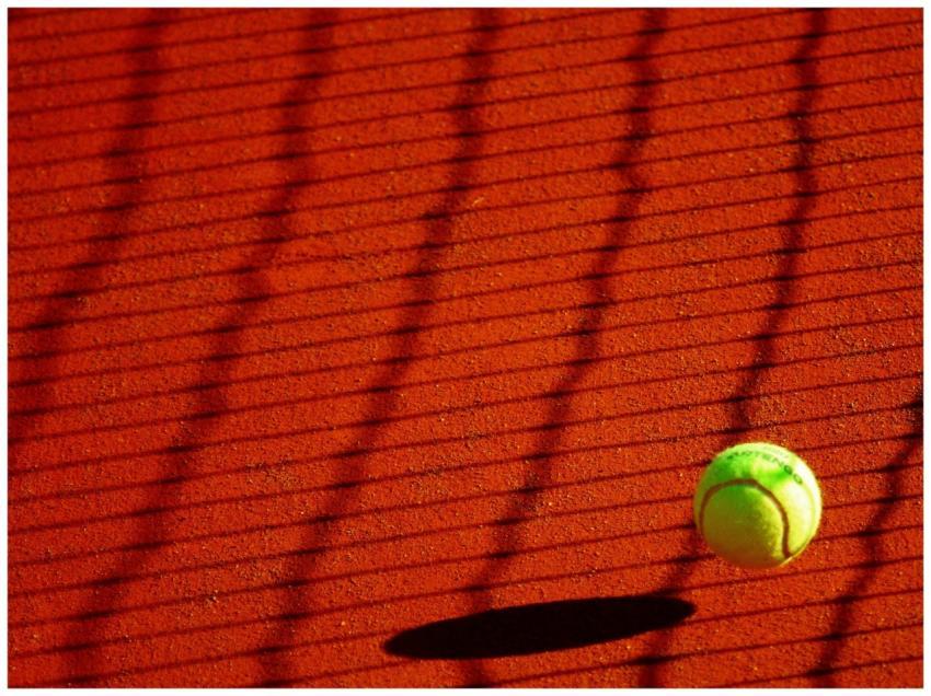 A vibrant tennis ball casting a shadow on a sunlit