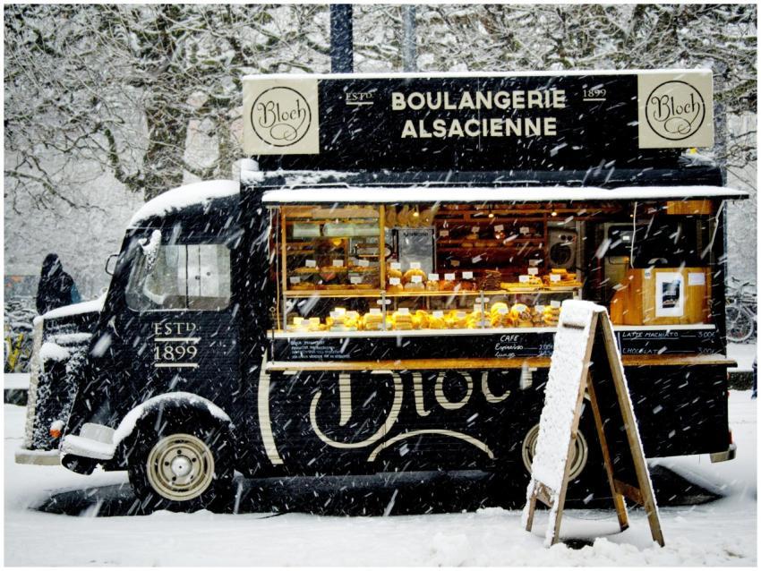 A vintage food truck in a snowy urban setting, off